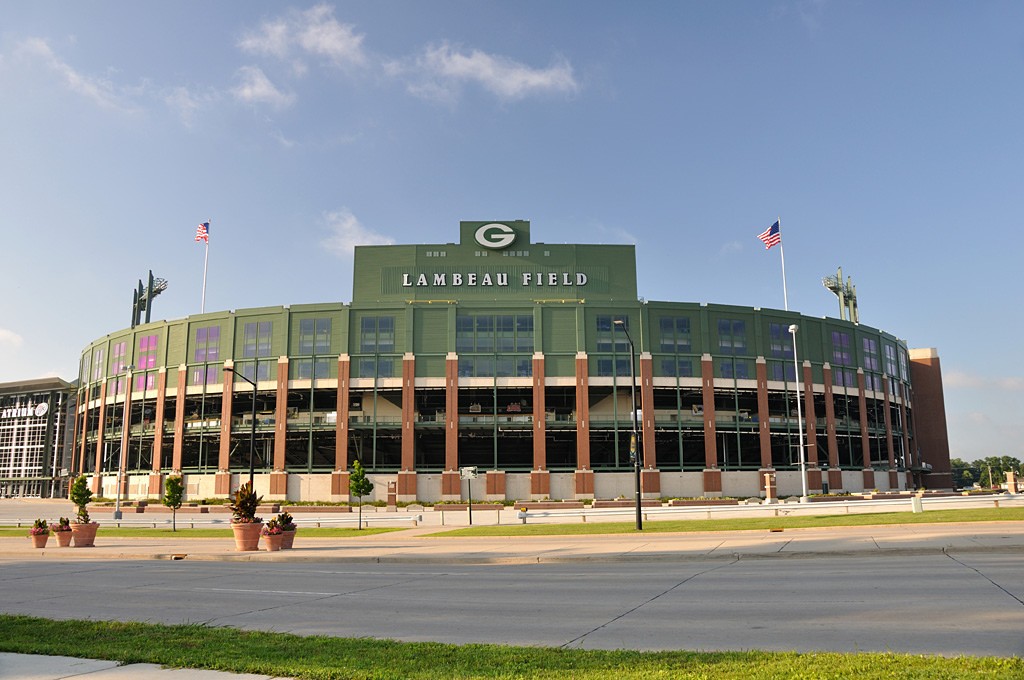 Lambeau Field in Green Bay under a blue sky, flags flying above the stadium bowl