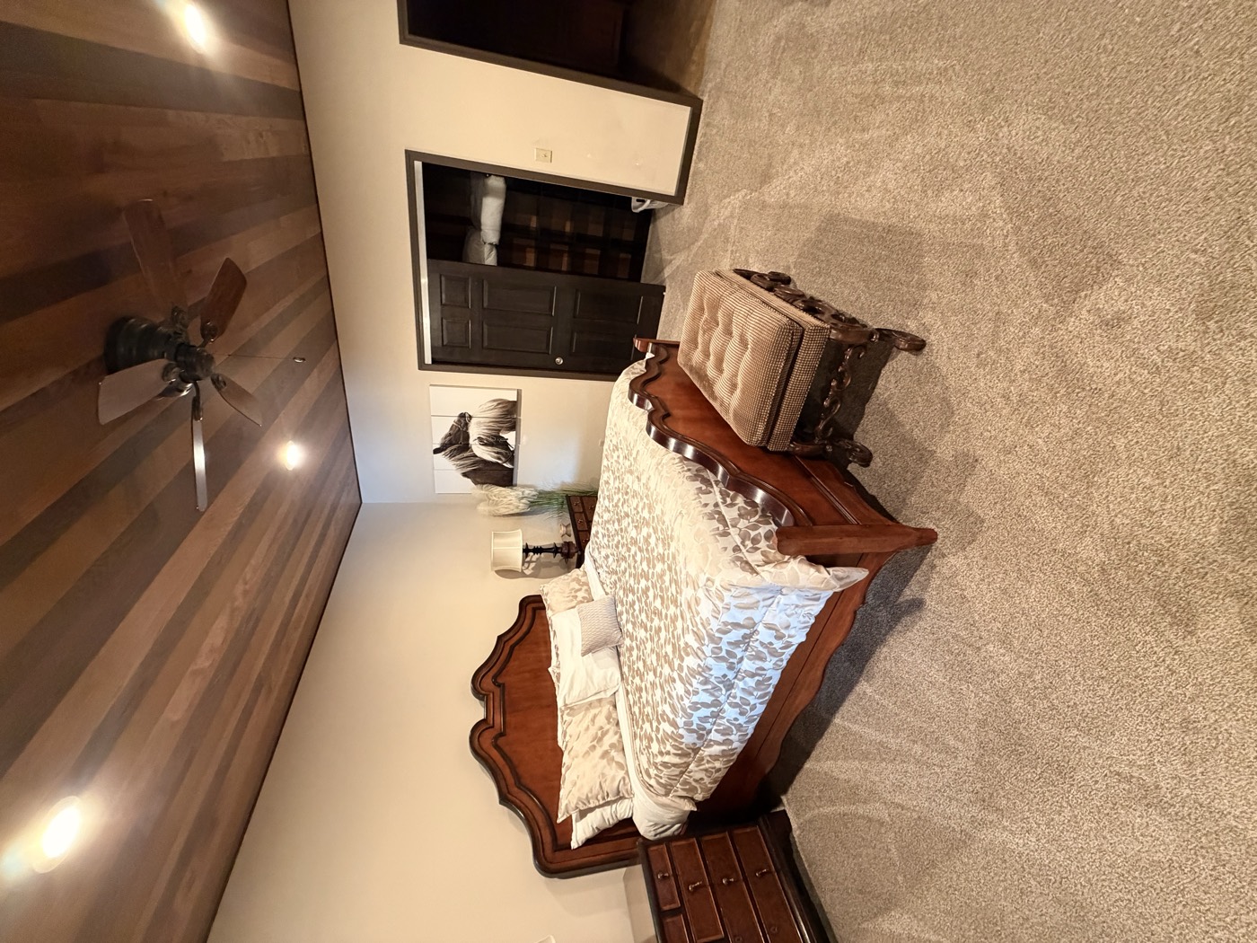 A bedroom with a carved wooden bed frame under a wood-plank ceiling