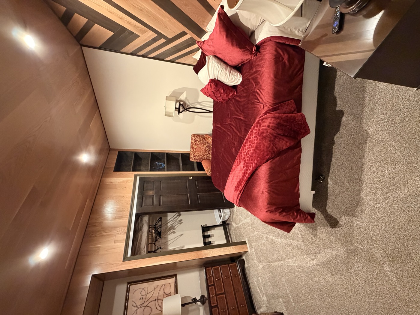 A bedroom with a patterned wood accent wall behind the bed