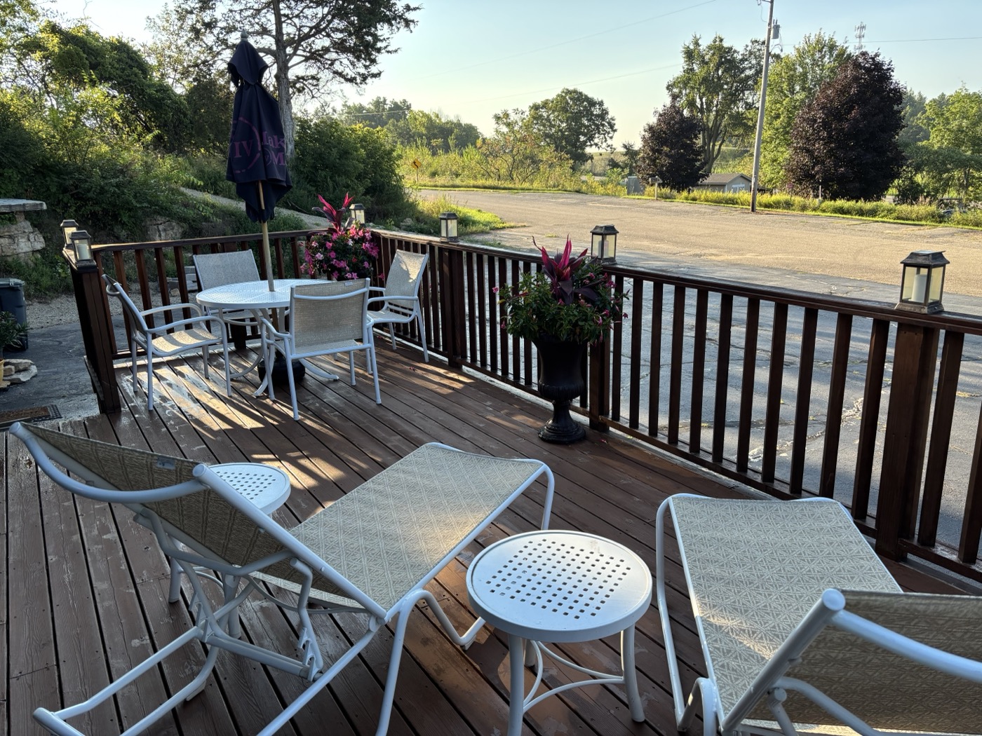 The open deck in morning light — loungers, a table under an umbrella, planters on the rail