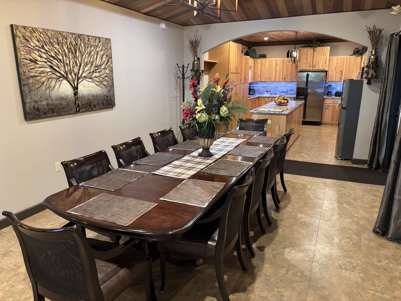 The dining table set for twelve, the kitchen open beyond the archway